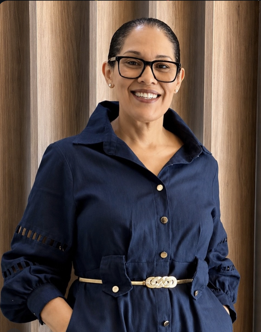 Dra. Karina Pitel sorrindo, de óculos e vestido azul-marinho
